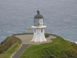 Der weiße Leuchtturm am Cape Reinga auf einer Landzunge über dem Meer