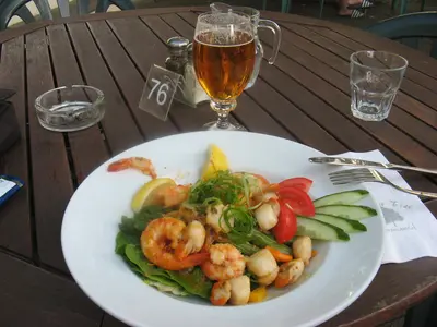 Teller mit Meeresfrüchten und ein Glas Bier auf einem Holztisch