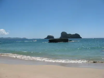 Sandstrand mit Blick auf Felseninseln im Meer