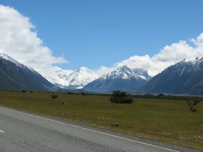 Straße ins Tal, im Hintergrund schneebedeckte Berge
