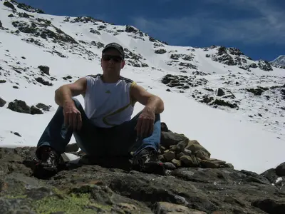 Ein Reisender sitzt auf einem Felsen im Schneefeld