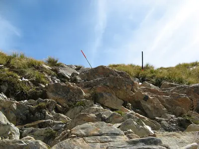 Felsen und eine Wegstange am Grat